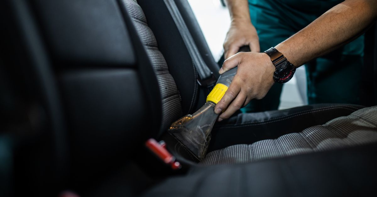 Person doing mobile detailing on a car seat with a vacuum